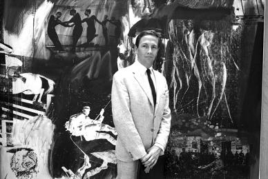 black and white photo of man in suit in front of large art